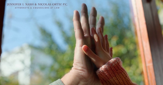 mother and daughter's hands touch through glass