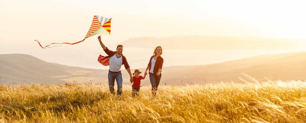 Family Running Through a Field with a Kite